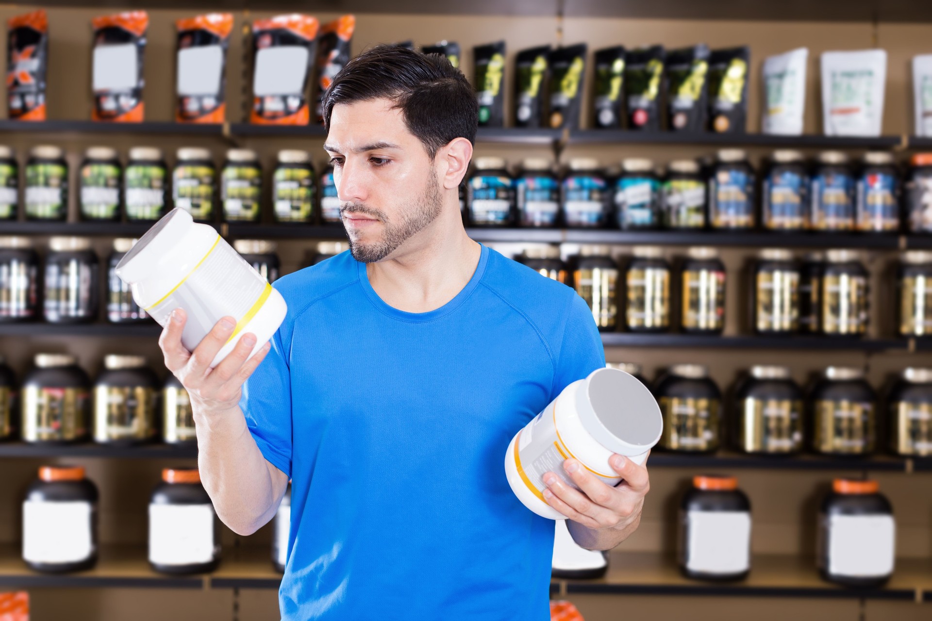 Attractive sport man looking different sport nutrition products
